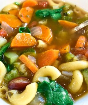 close up of minestrone soup in white bowl