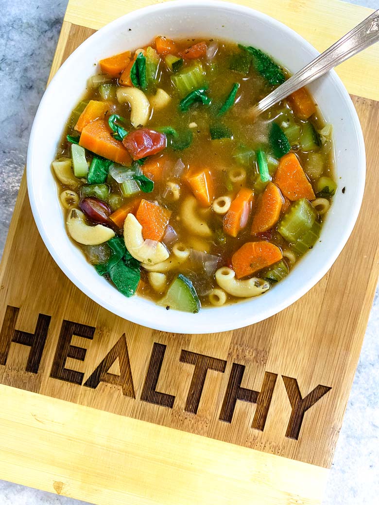 minestrone soup in white bowl on cutting board