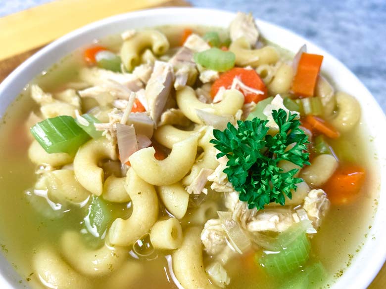 close up of turkey carcass soup in a white bowl