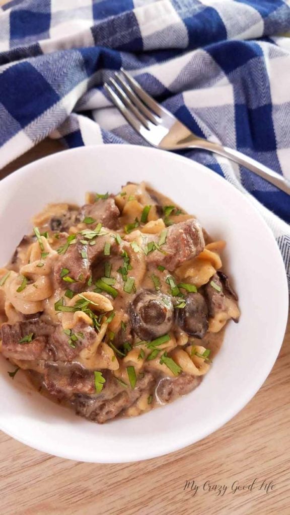 Beef Stroganoff in a white bowl with a blue and white napkin