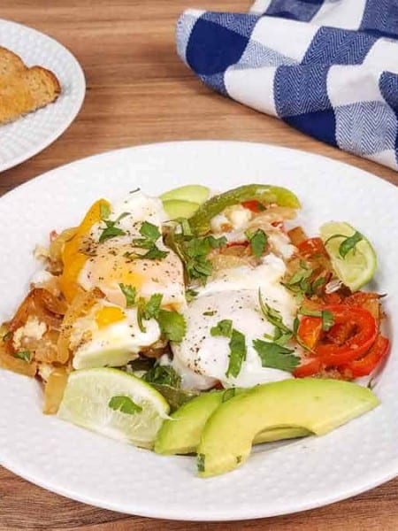 white plate with breakfast fajitas and a plate of toast in the background