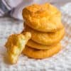 Four pieces of cloud bread stacked on top of each other with one half piece resting on the stack, and all of the cloud bread is sitting on top of a white napkin.