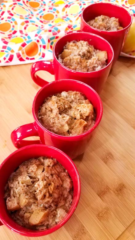 baked oatmeal in four red coffee mugs, lined up vertically on wood table