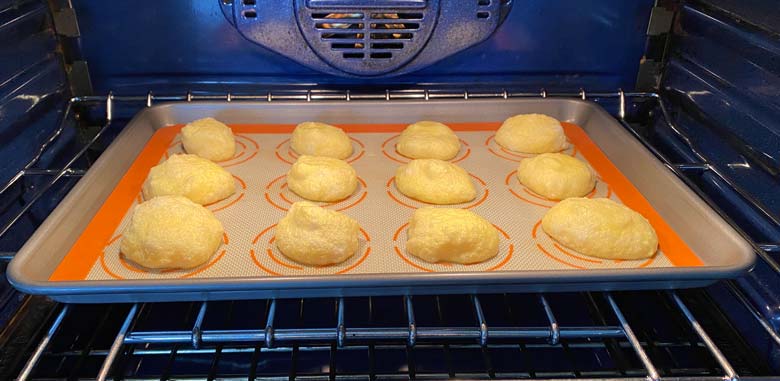 cloud bread cooking in the oven on a baking sheet with a silpat mat