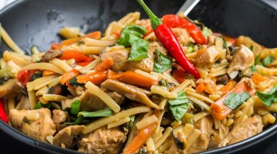 close up of cooked and plated drunken noodles in black matte bowl
