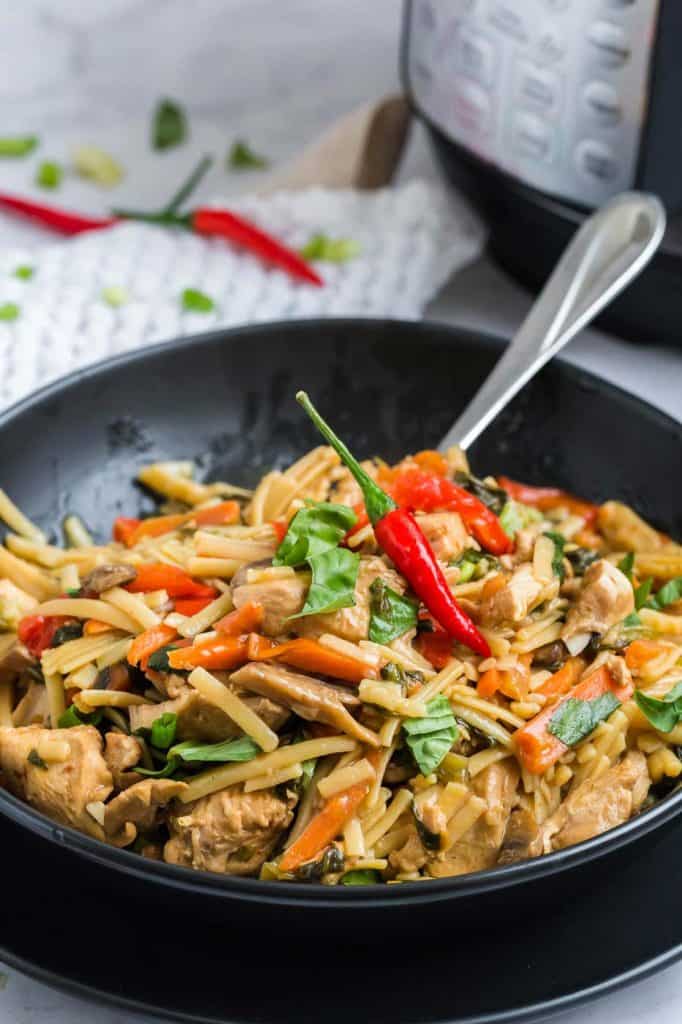 close up of cooked and plated drunken noodles in black matte bowl