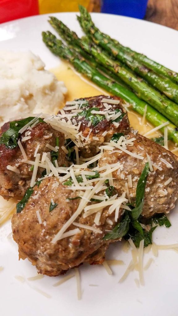 close up of healthy swedish meatballs on white plate with asparagus