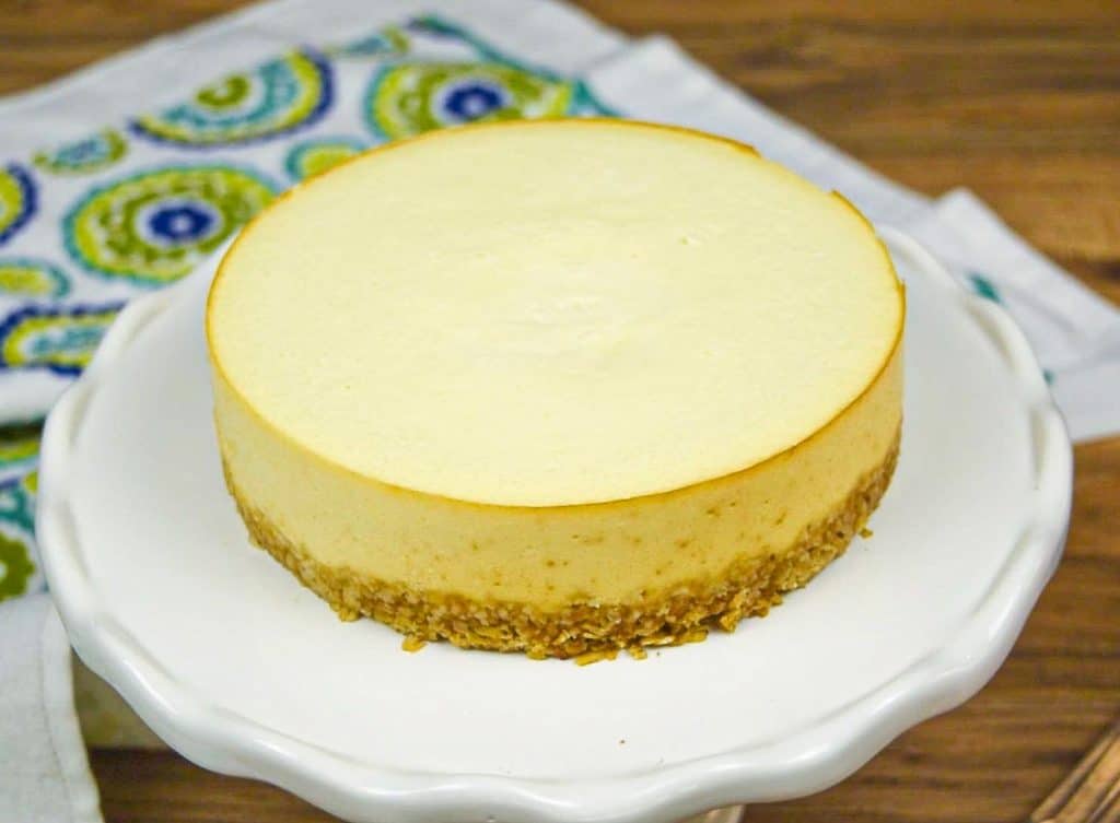 undecorated cottage cheese cheesecake on white cake stand