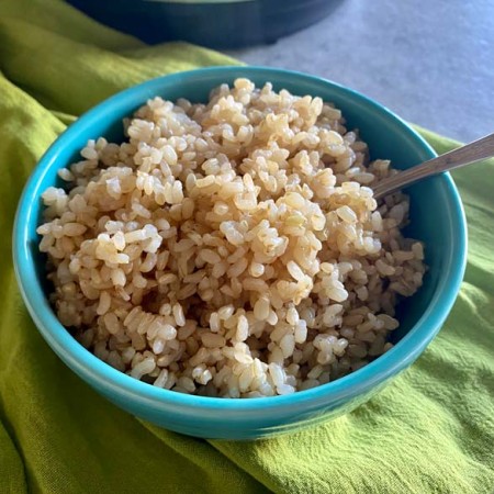close up of brown rice in a blue bowl with spoon