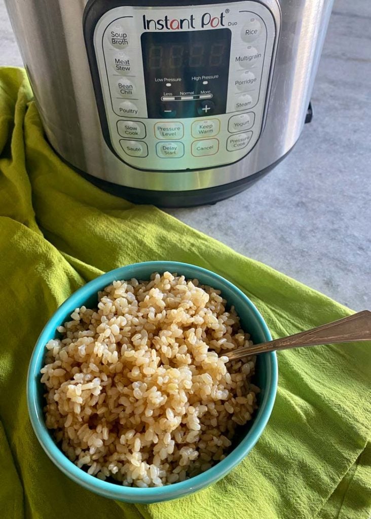 blue bowl of brown rice in front of an instant pot