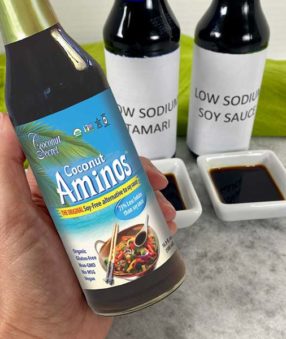 hand holding bottle of coconut aminos