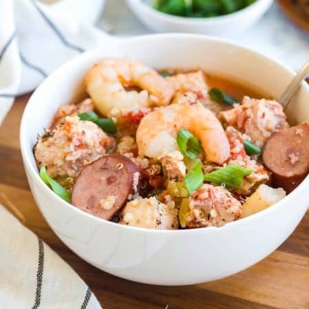 white bowl with jambalaya on top of a wood board