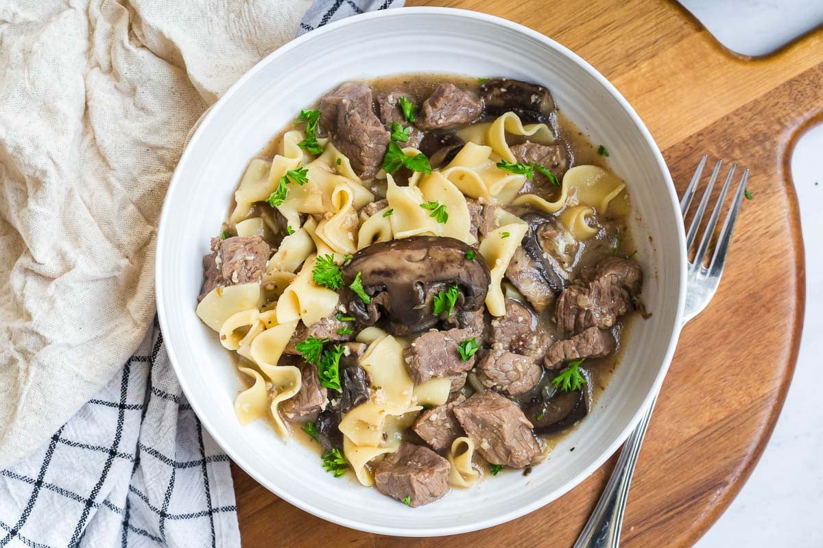 white bowl on a wood counter with beef stroganoff.