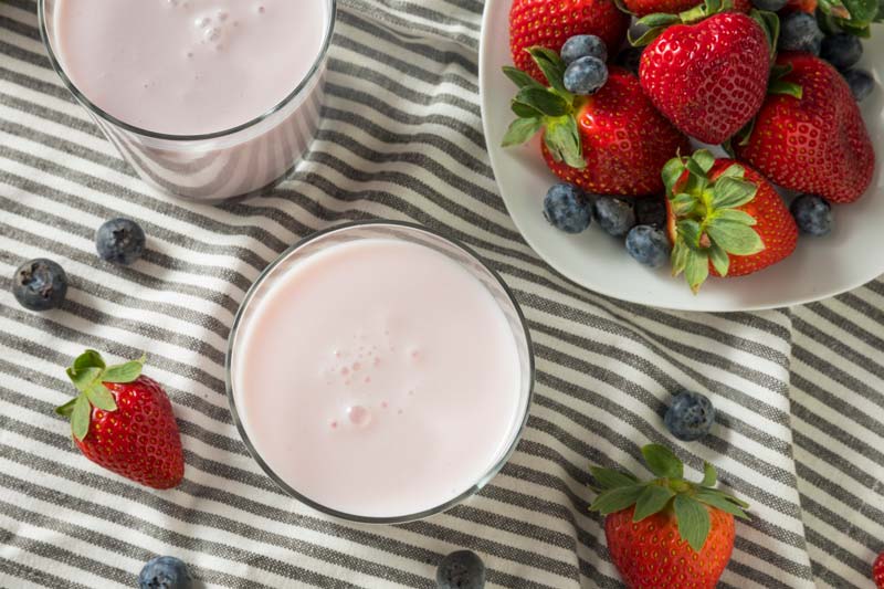 drinkable yogurt with gellan gum in a clear glass with berries on table