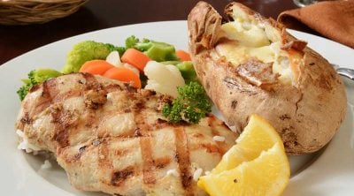 grilled chicken, vegetables, and a baked potato on a white plate