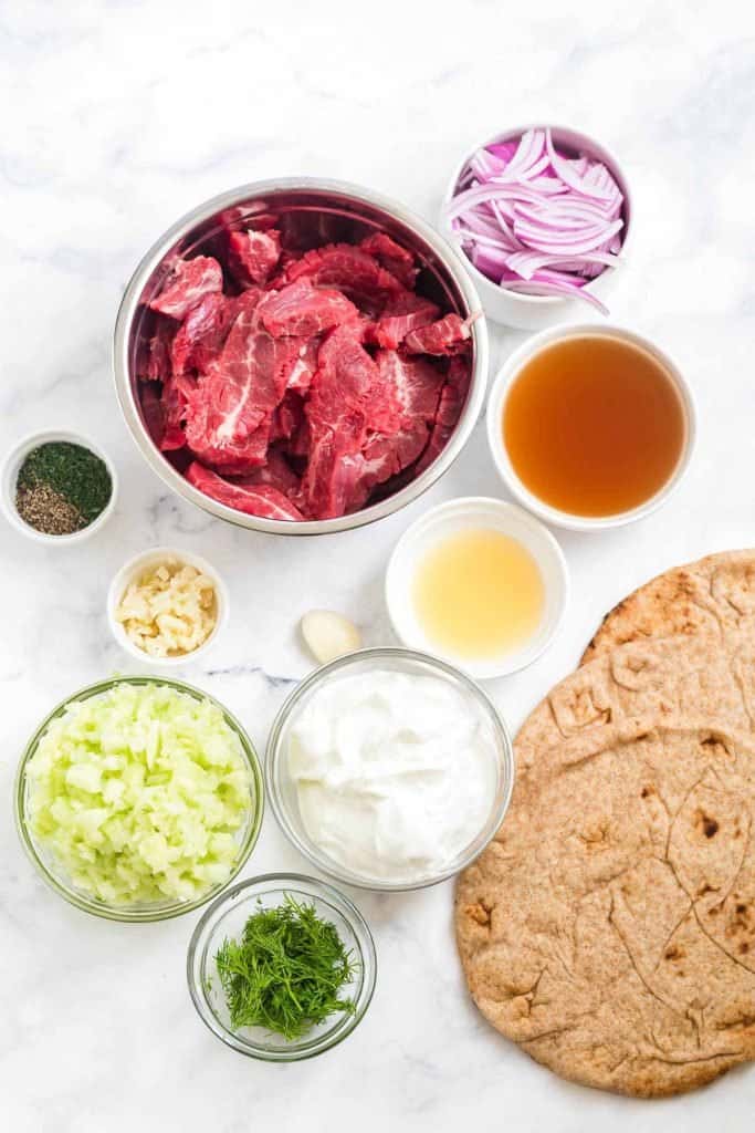 bowls of ingredients needed for beef gyros on a white counter 