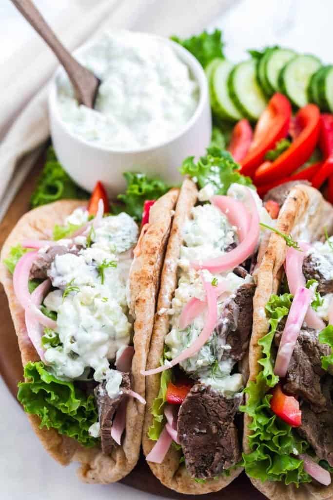 beef gyros, toppings, and tzatziki sauce arranged on a dish