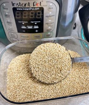 dry quinoa in a measuring cup in front of an Instant Pot