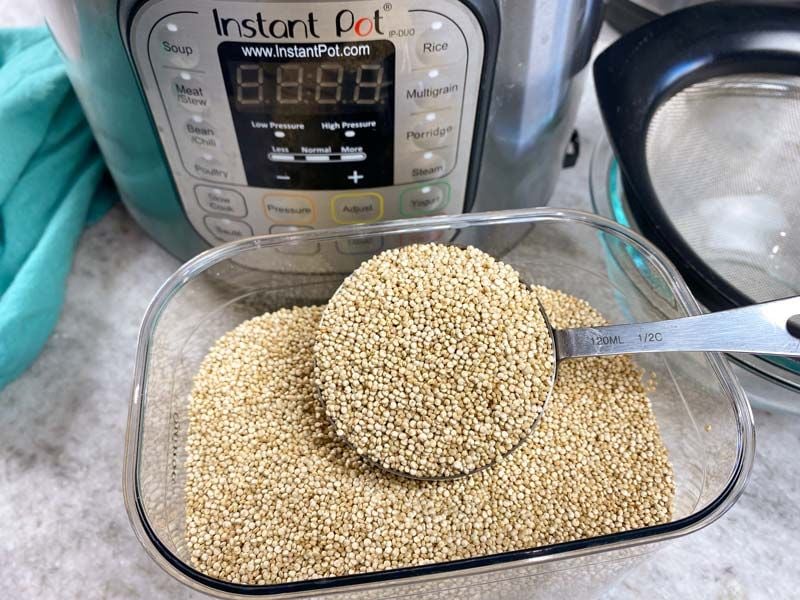 dry quinoa in a measuring cup in front of an Instant Pot