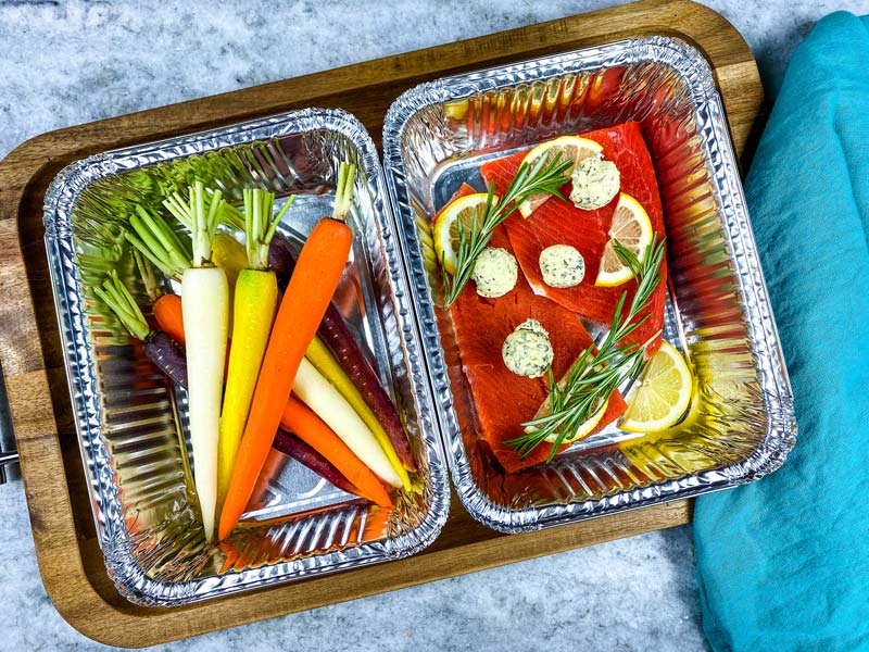 peeled carrots and grilled salmon in foil tins