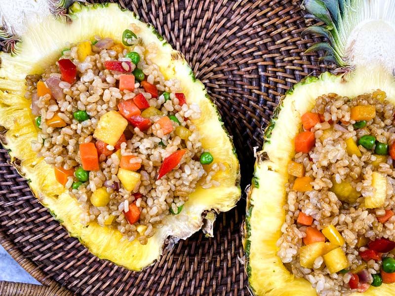 two halves of pineapple with pineapple fried rice inside