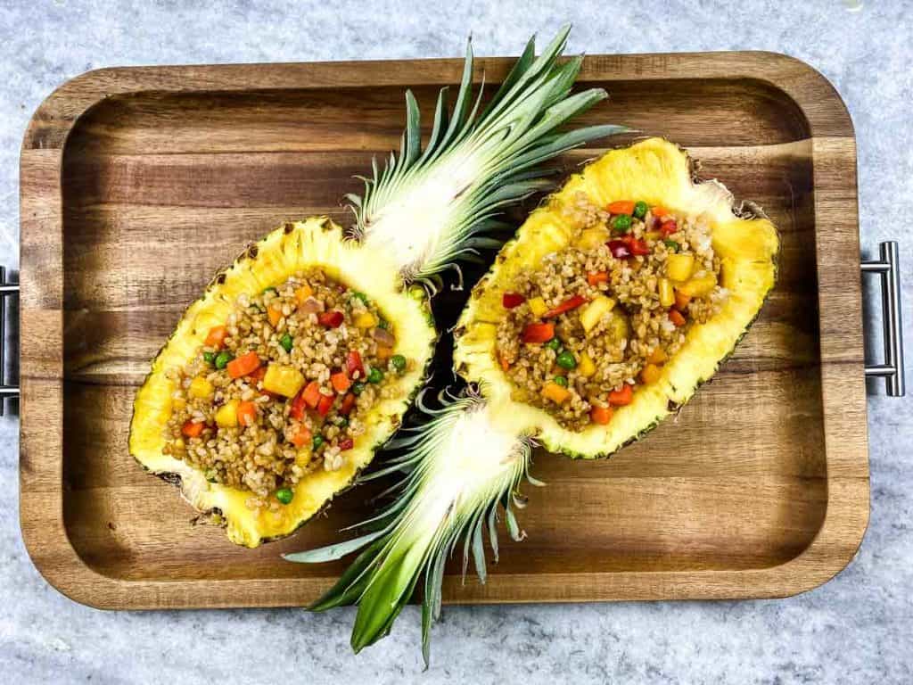 two pineapple halves filled with vegan fried rice