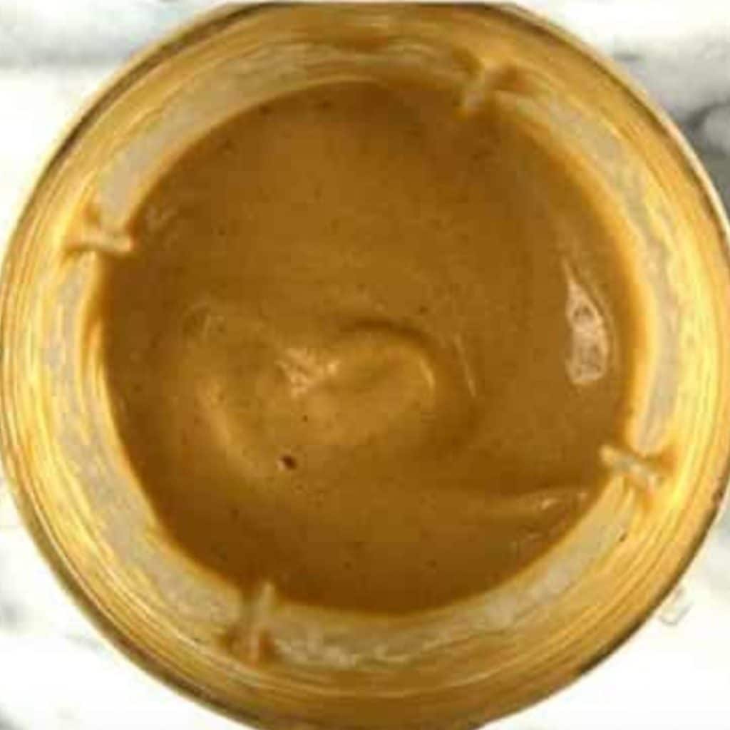 A blender with blended bananas, almond milk, cocoa powder and vanilla extract.