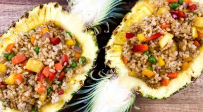 two halves of pineapple with pineapple fried rice inside