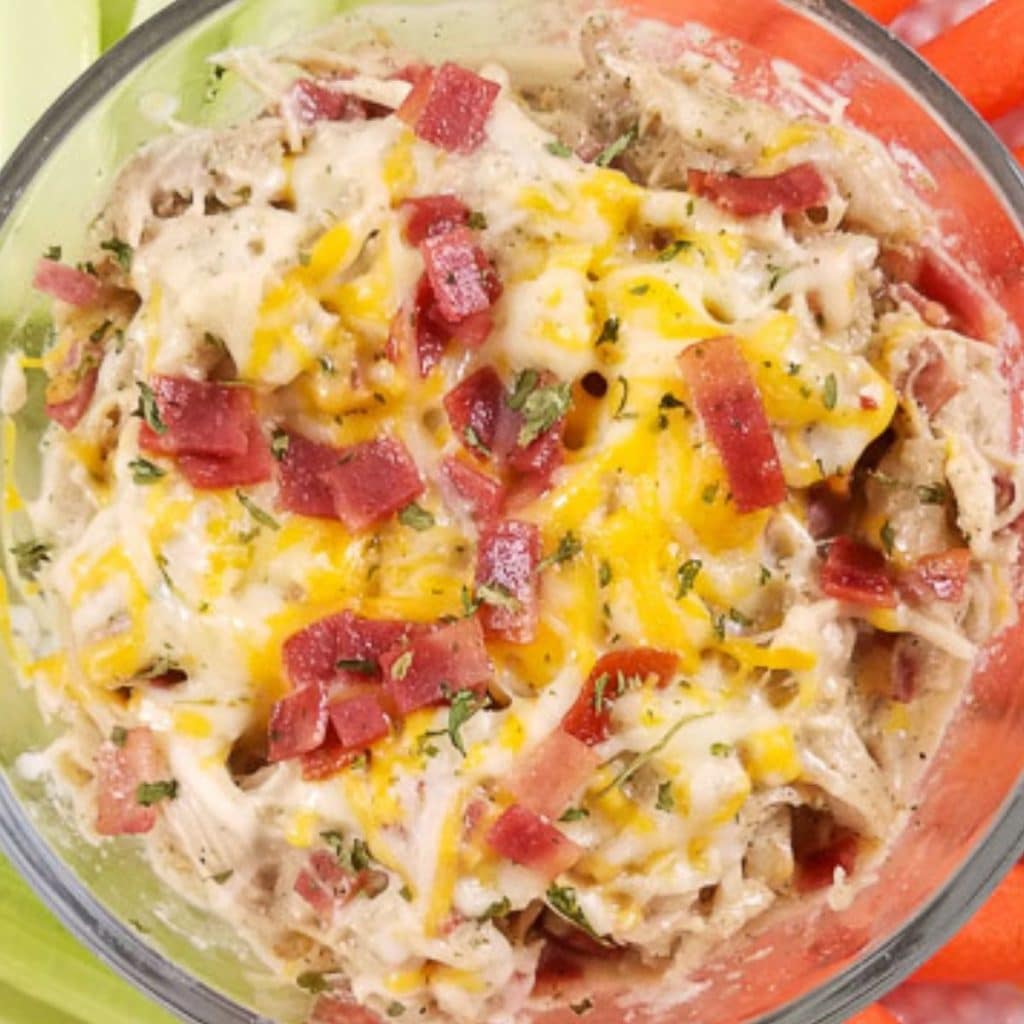 A glass bowl with creamy, cheesy, chicken and bacon.