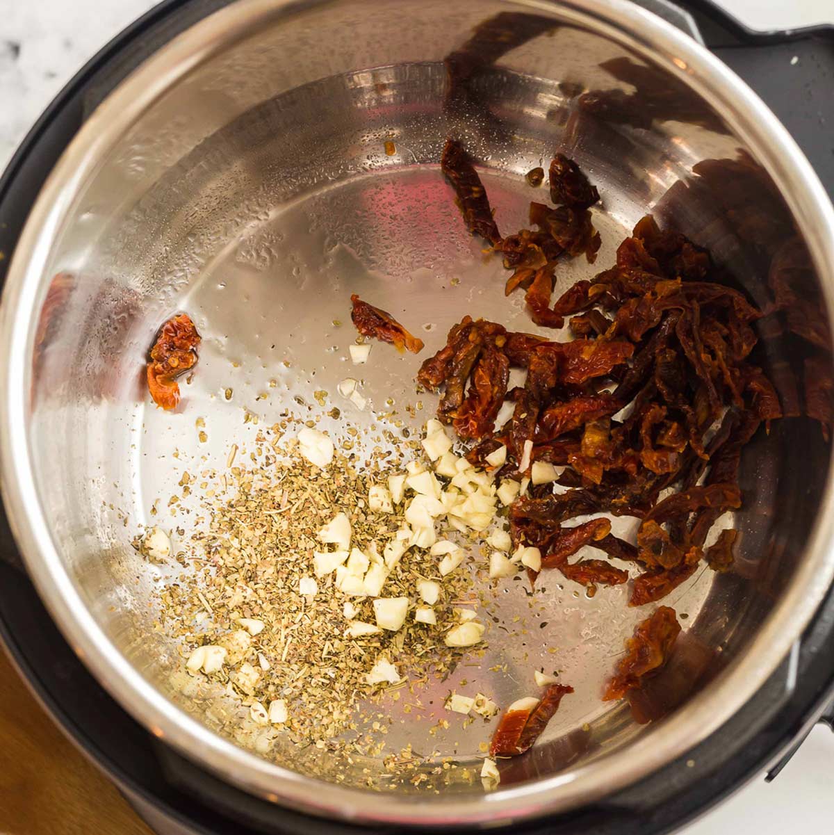 garlic, spices and sun dried tomatoes being sautéed in an instant pot.