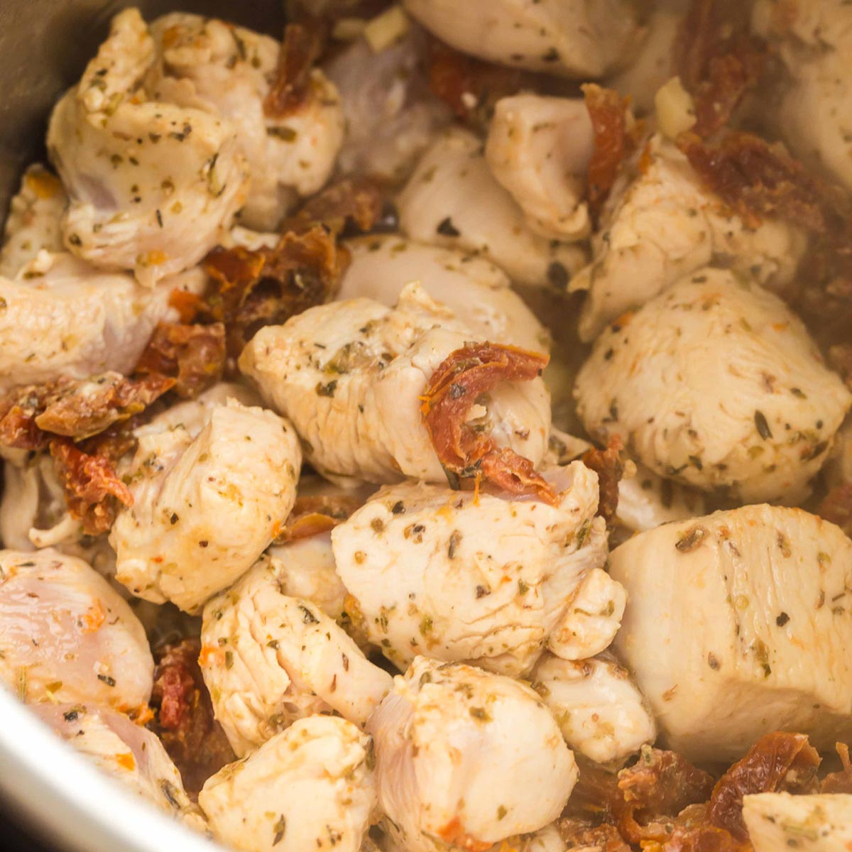 close up view of cubed chicken being cooked in an instant pot.