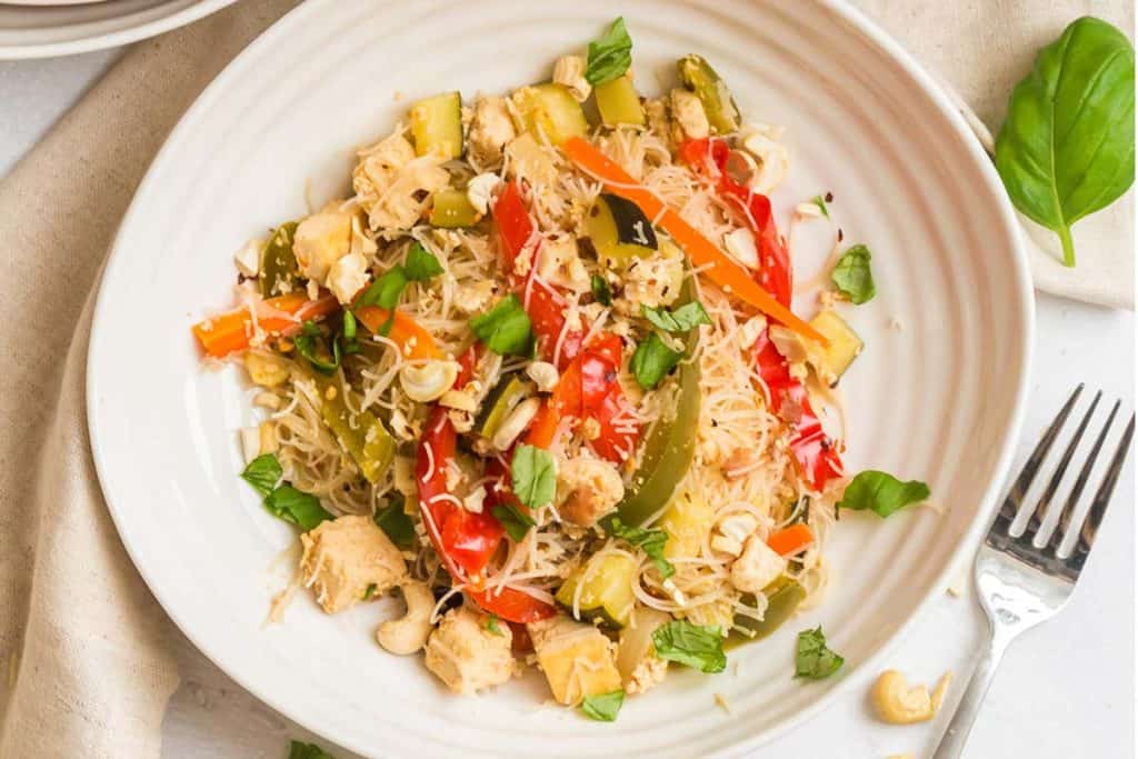 White plate with pad thai and an artful drizzle of sriracha.
