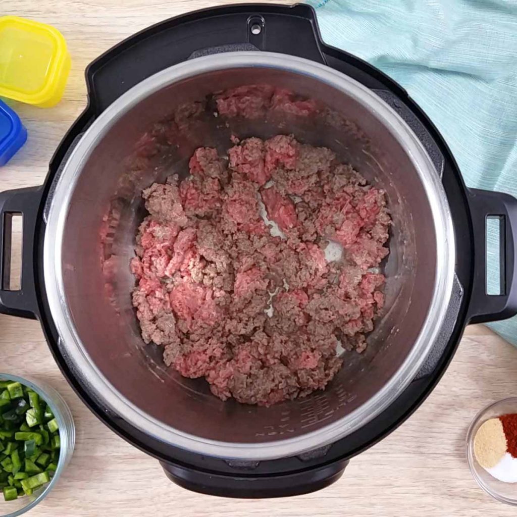 Open Instant Pot with cooking ground beef inside.