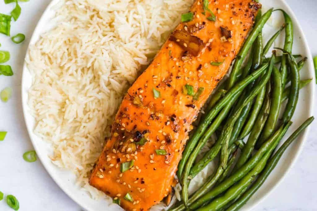 salmon fillet, white rice, and green beans on a white plate