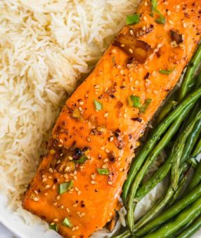 salmon fillet, white rice, and green beans on a white plate