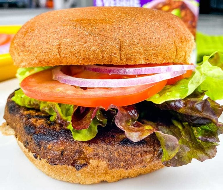 close up of black bean burger with veggies and a bun.