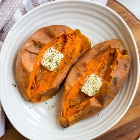 two cooked whole sweet potatoes, cut in half and dressed with butter and dried parsley.