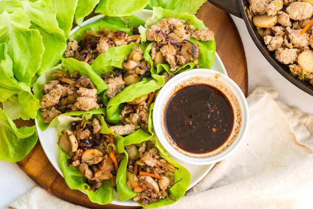 plate of lettuce with ground turkey filling and a bowl of dipping sauce