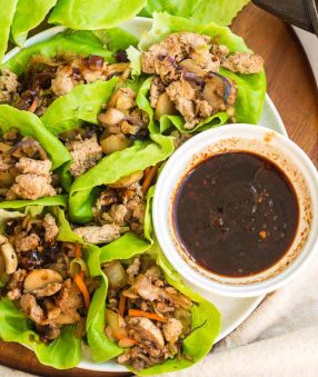 plate of lettuce with ground turkey filling and a bowl of dipping sauce