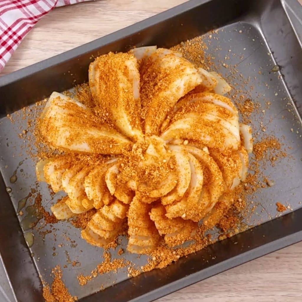 A baking sheet with a seasoned blooming onion ready to bake.