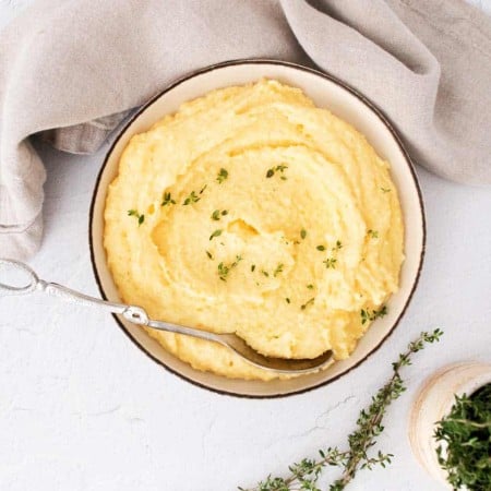 White bowl of creamy polenta on a white counter.
