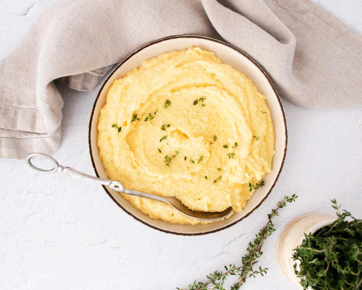 White bowl of creamy polenta on a white counter.