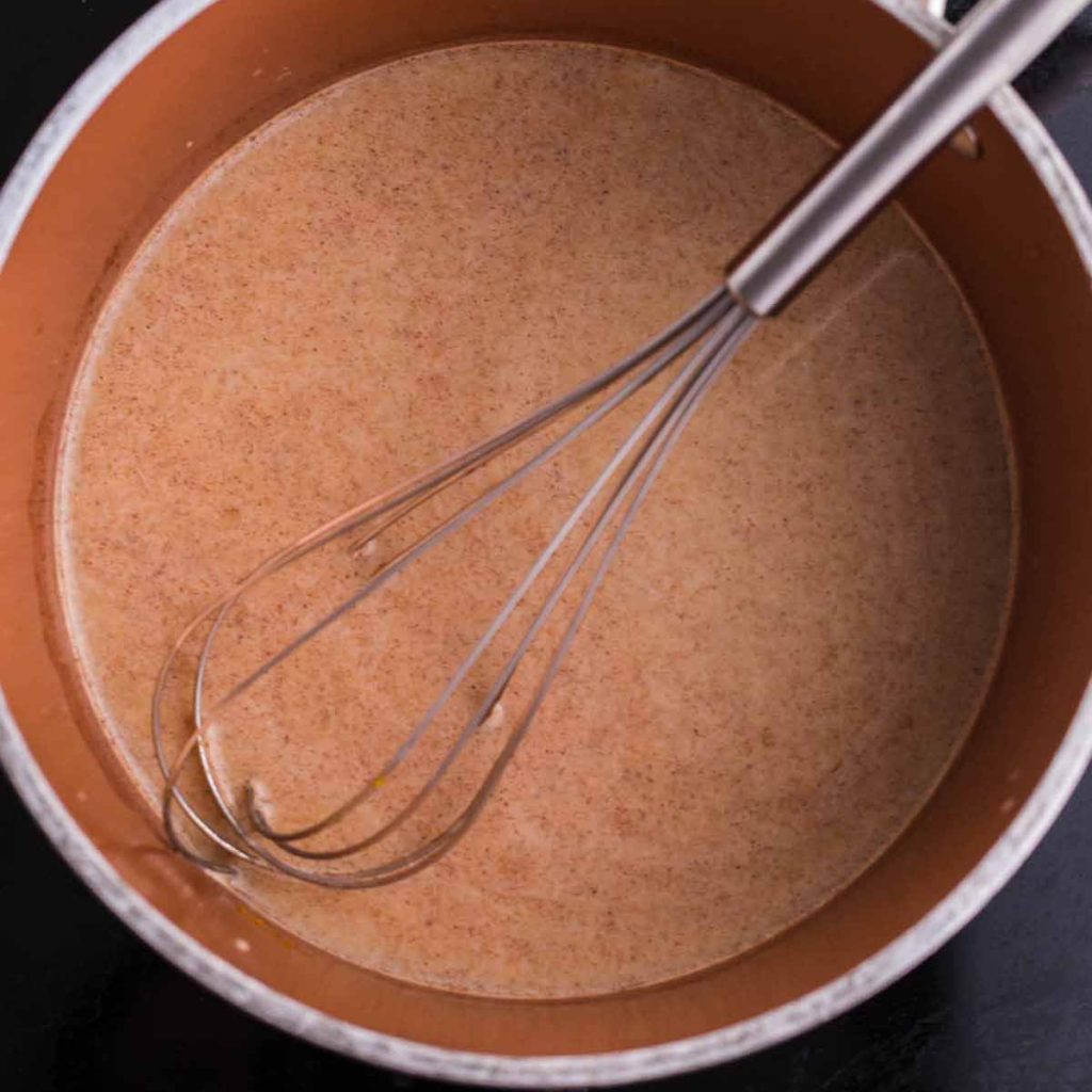 A pot on the stove with ingredients for Pumpkin Cold Brew coffee being whisked together.