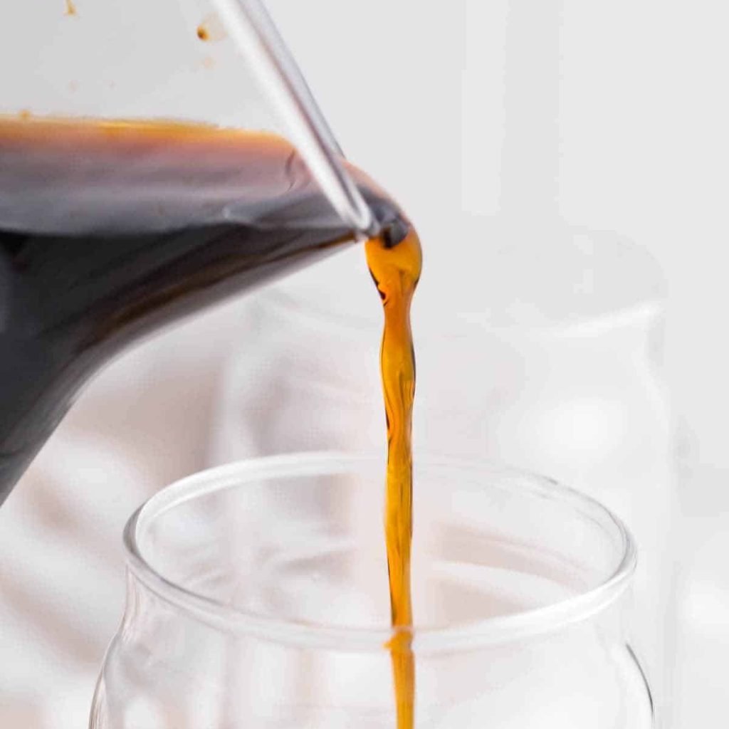 Chilled cold brew coffee being poured into drinking glasses.