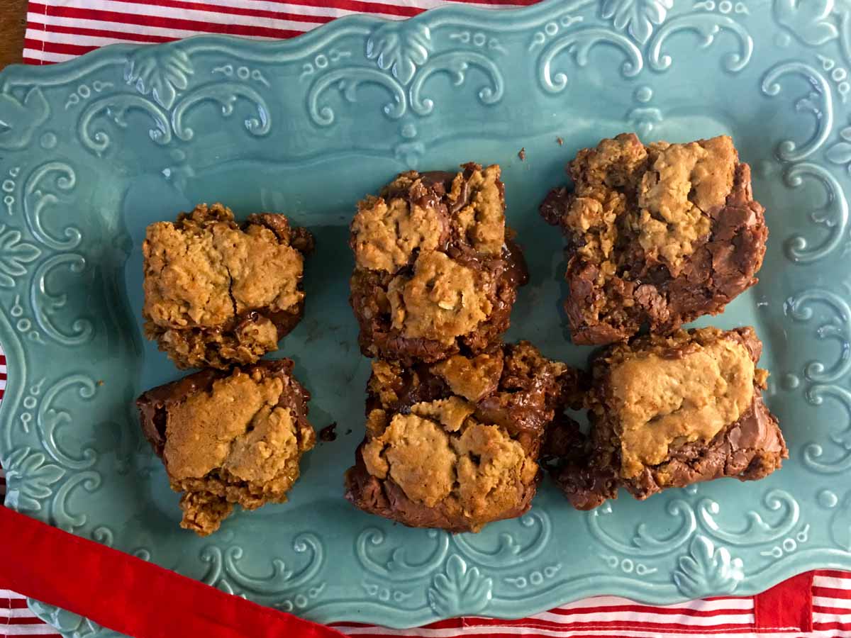 Six oatmeal revel bars cut and sitting on a light blue platter with a red and white napkin underneath.