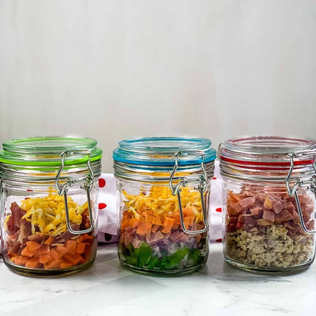 three mason jars with colorful lids, full of omelette ingredients to make egg cups