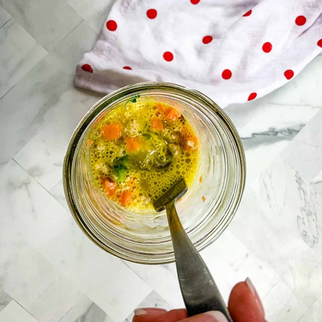 view from above of a mason jar with vegetables and a mixed in egg