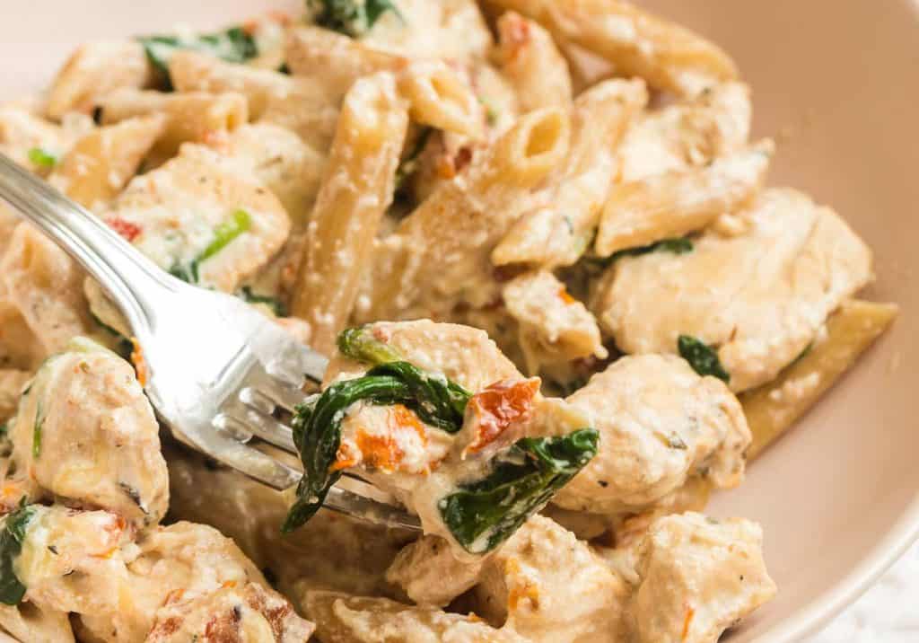 close up of bite of tuscan chicken on fork