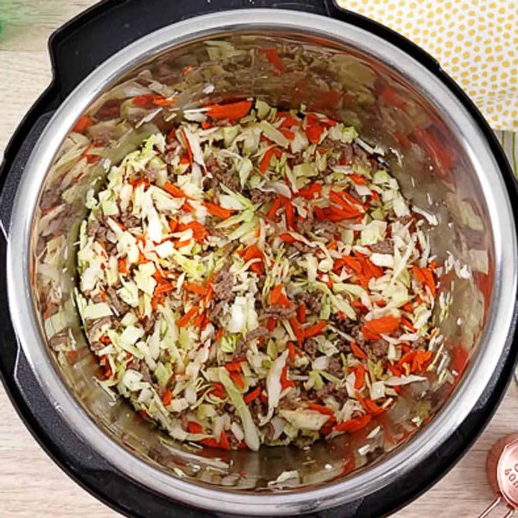 Open Instant Pot with ingredients for egg rolls inside. 