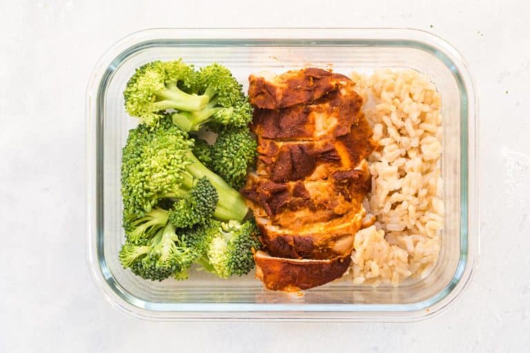 Broccoli florets, sliced chipotle chicken breast and cooked brown rice inside of a glass meal prep container.